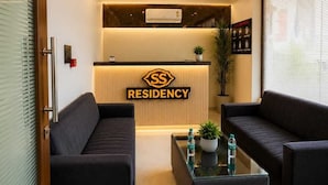 Un área de recepción moderna con un mostrador, dos sofás, una mesa de centro y un ventilador de techo.
