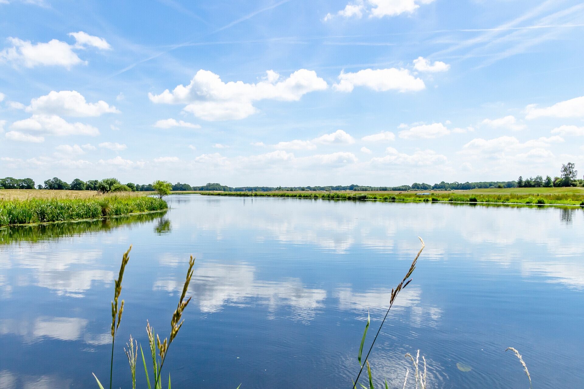 A calm river with grassy banks and a clear sky.