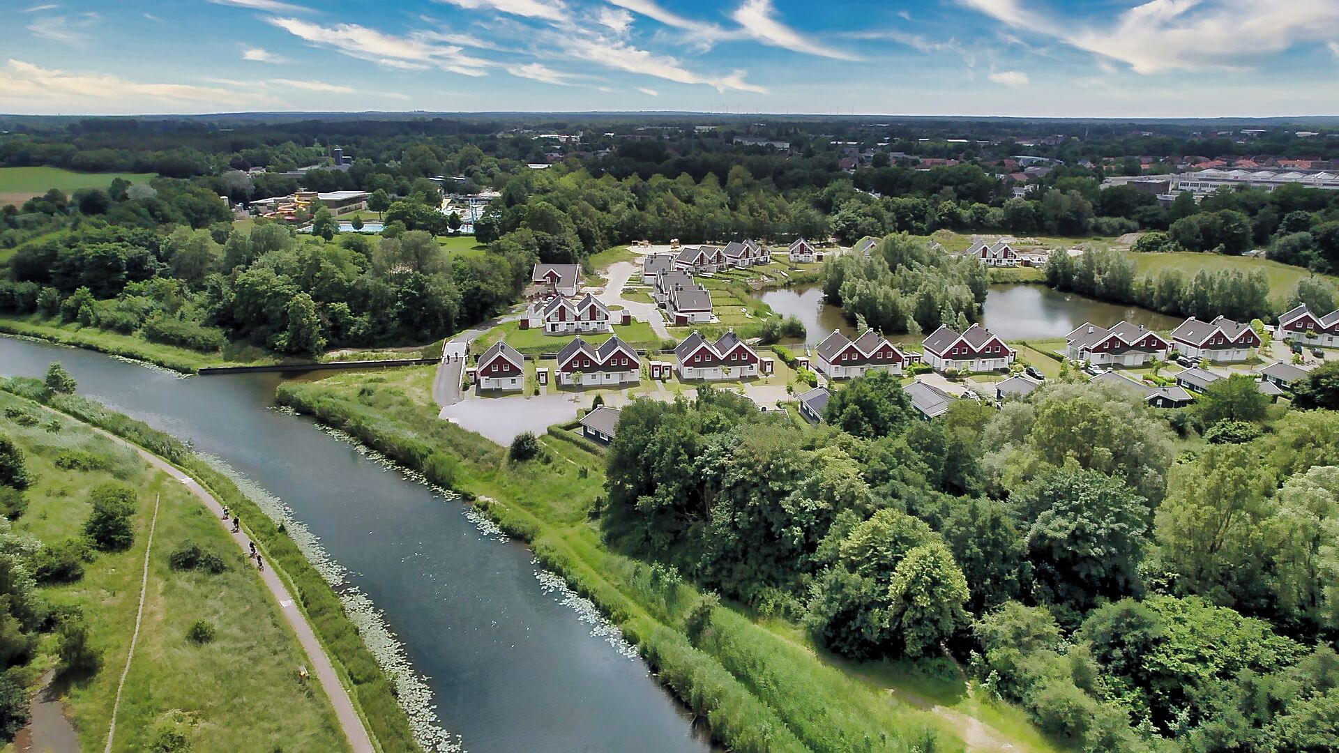A residential area with houses arranged around a central water body, surrounded by greenery.