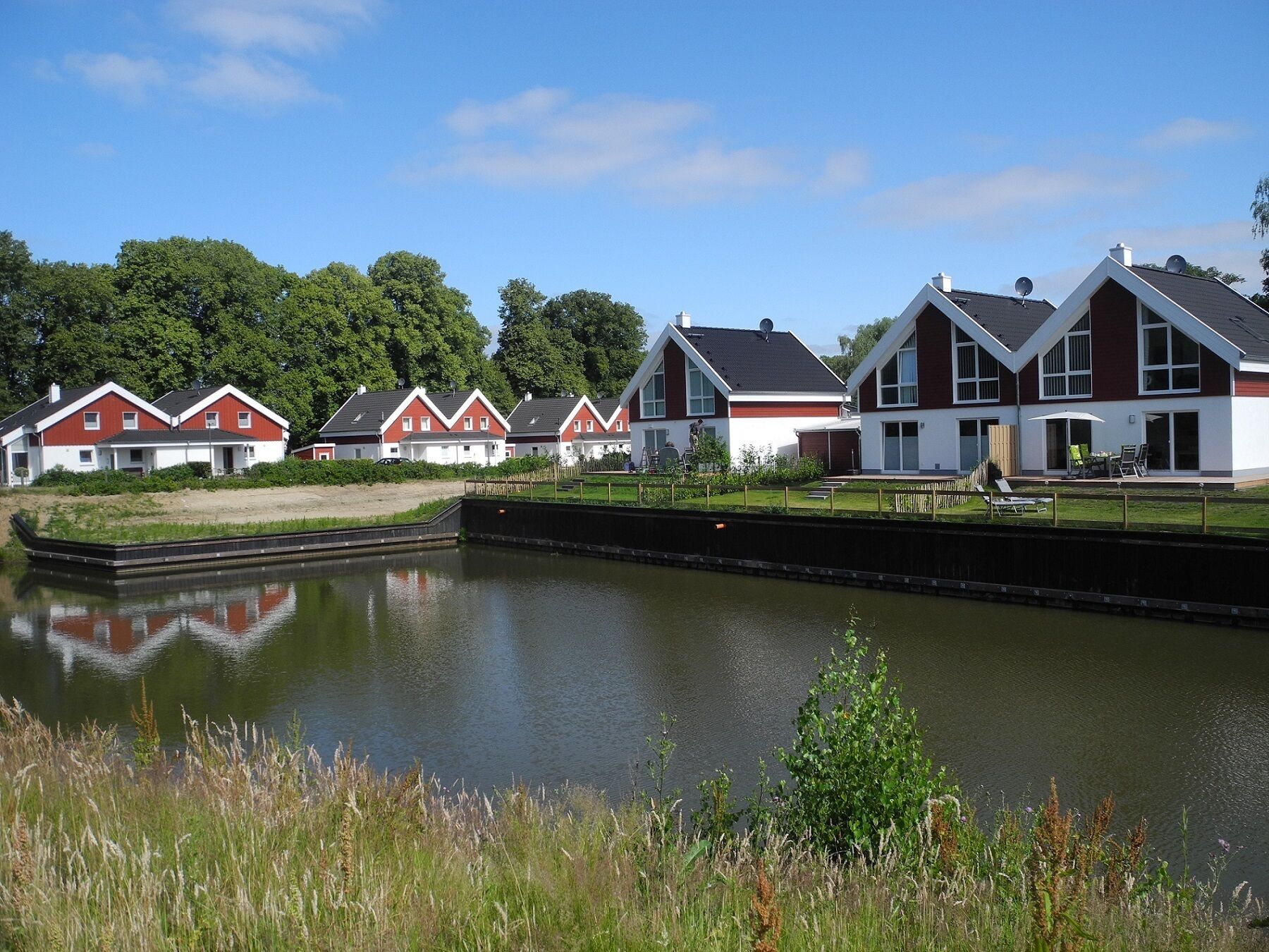 Moderne Häuser an einer Reihe mit einem Kanal im Vordergrund.