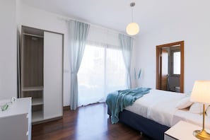 A bedroom with a bed, a bedside table, a wardrobe, a window with curtains, and a hanging light fixture. - Luxury Vacation Seaside Villa With Privacy (Çeşme)