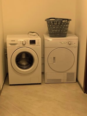 A laundry area with two washing machines and a basket. - Luxury Vacation Seaside Villa With Privacy (Çeşme)