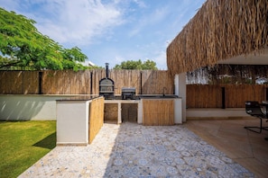 An outdoor kitchen area with a grill, a seating area, and a patterned tile floor. - Luxury Vacation Seaside Villa With Privacy (Çeşme)