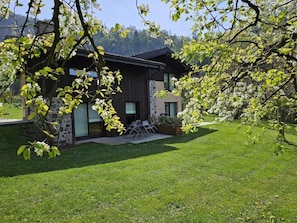 A modern house with a patio, surrounded by a well-maintained lawn and trees. - Quader nidi nel verdde (Lombardia)