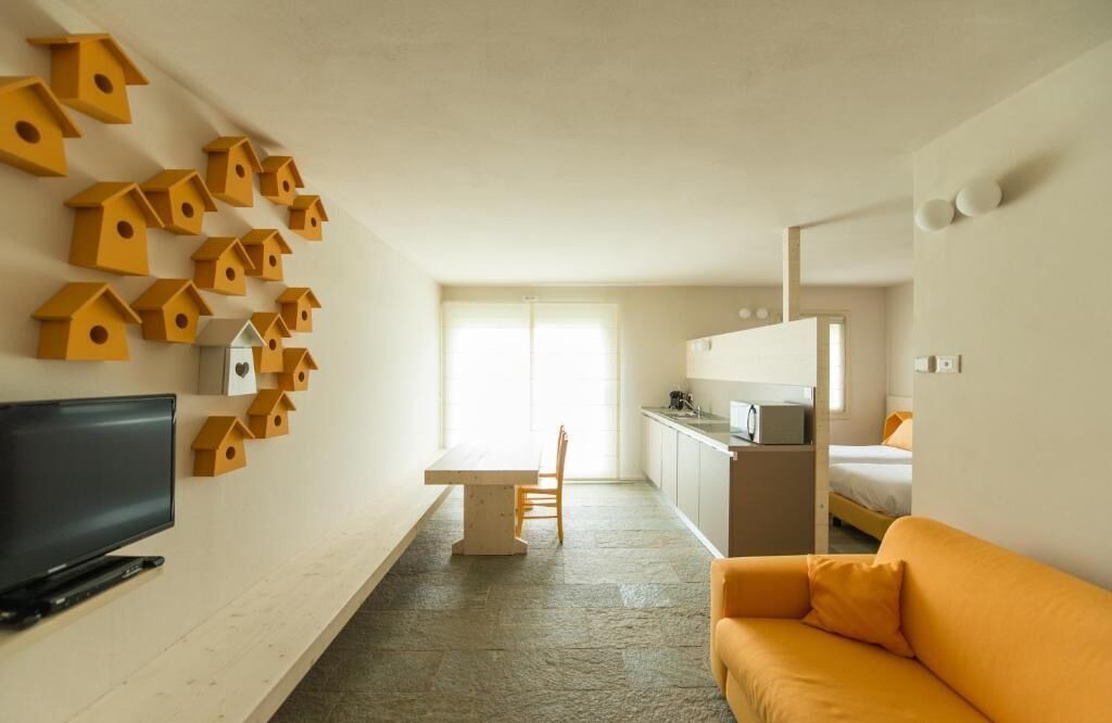 A hotel room with a TV, a dining table, a kitchen area, and a bed.