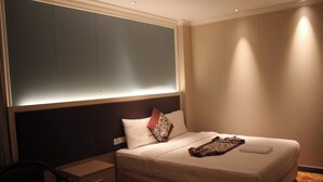 A hotel room with a bed, bedside table, chair, and a large window with blinds. - Gold Indigo Hotel (Phnom Penh)