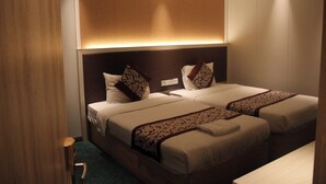 A hotel room with two beds, a wooden headboard, and a wall-mounted light fixture. - Gold Indigo Hotel (Phnom Penh)