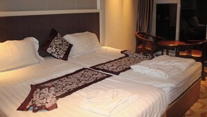 A hotel room with two beds, a sitting area with a table and chairs, and a large window. - Gold Indigo Hotel (Phnom Penh)