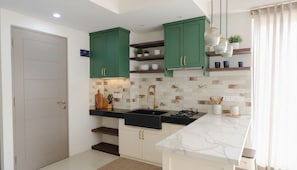 Una cocina moderna con gabinetes verdes, encimera negra y una isla de mármol blanco.
