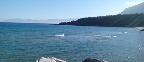 A coastal landscape with a clear sky, calm sea, and rocky shoreline.