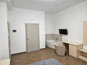 A bathroom with a bathtub, a toilet, a sink, and a television mounted on the wall.