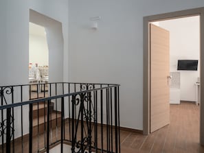 A modern interior with a staircase, a flat-screen TV, and a kitchen area.