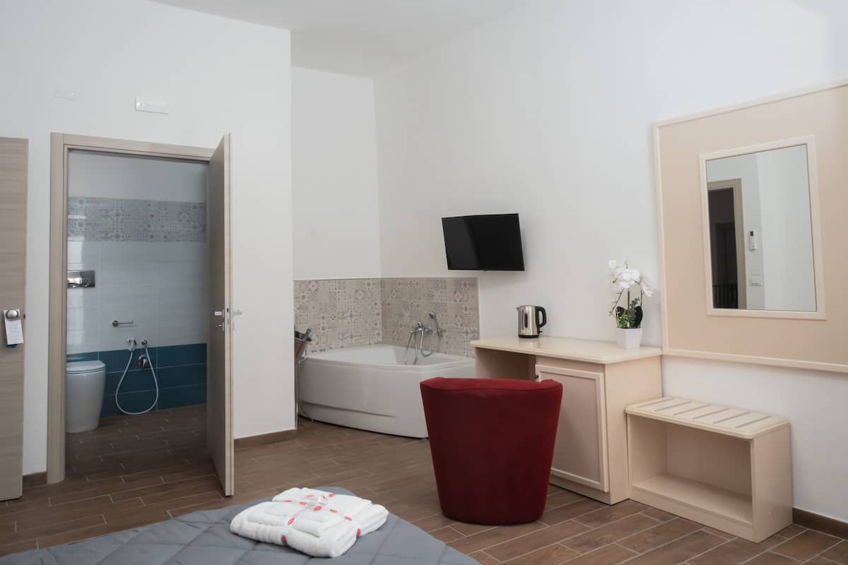 Une salle de bain avec une baignoire, des toilettes, une douche et une chaise rouge.