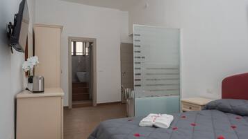 A bedroom with a bed, a wardrobe, a mirror, and a bathroom visible through an open door.