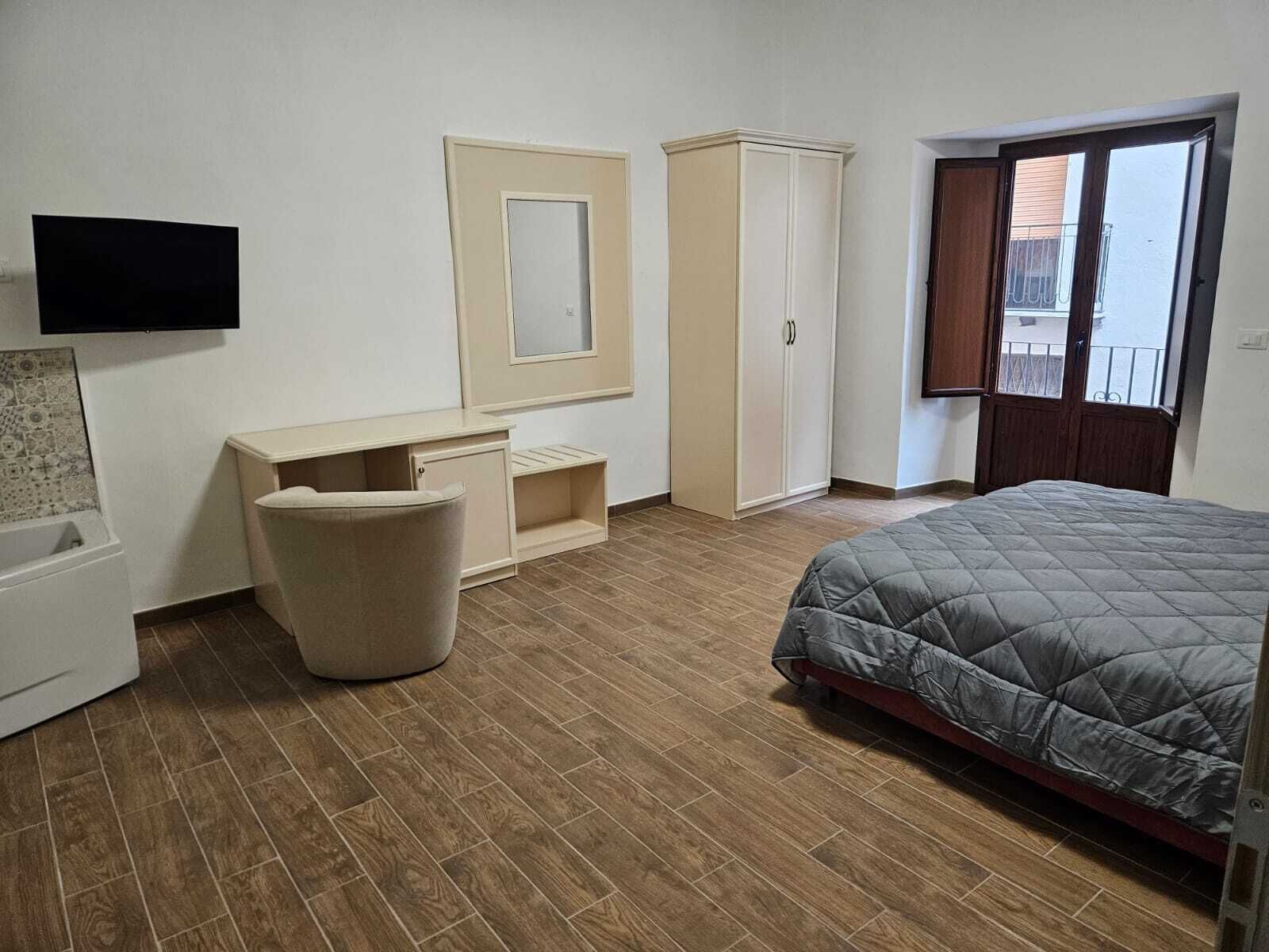 Una camera da letto con un letto, un armadio, una scrivania, una sedia e una televisione.