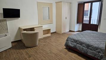 Una camera da letto con un letto, un armadio, una scrivania, una sedia e una televisione.