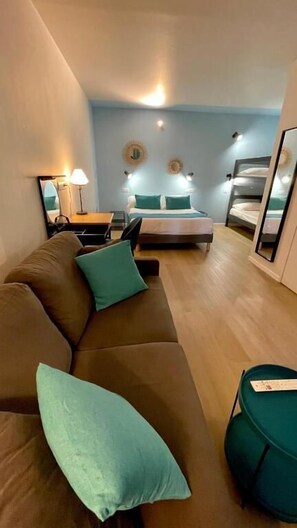 A modern hotel room with a sofa, a bed, a desk, and a mirror. - Hôtel Cantosorgue (L'Isle-sur-la-Sorgue)