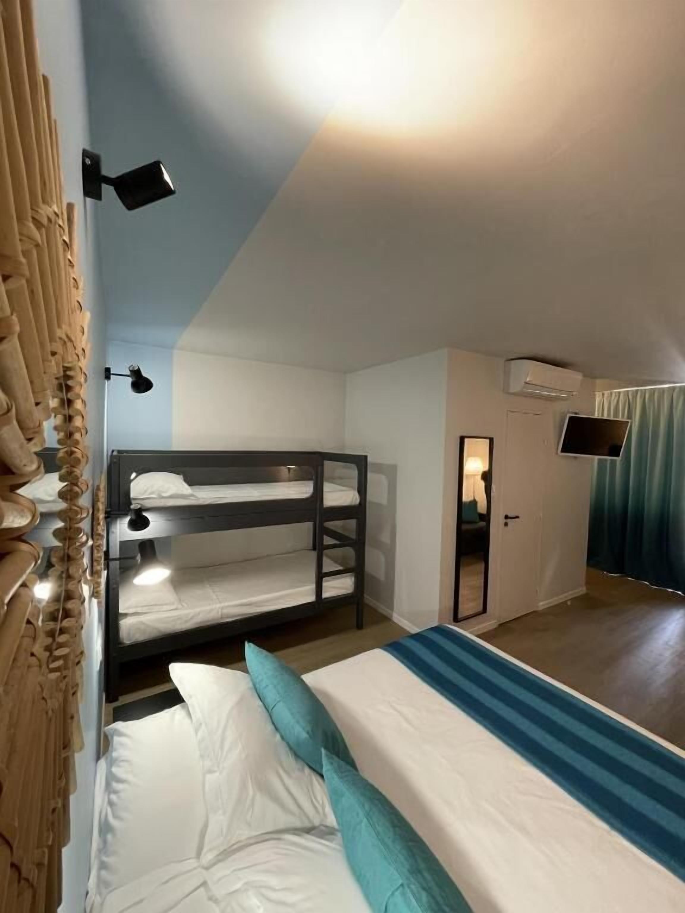 A room with bunk beds, a desk, a mirror, and a TV.
