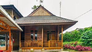 Ein Holzhaus mit Veranda, Ziegeldach und einem Garten mit rosa Blumen.