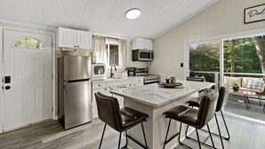 A modern kitchen with a central island, stainless steel appliances, and a view to the outdoors. - The Woods, Romantic Mountain escape with hot-tub under the stars! (Hedgesville)
