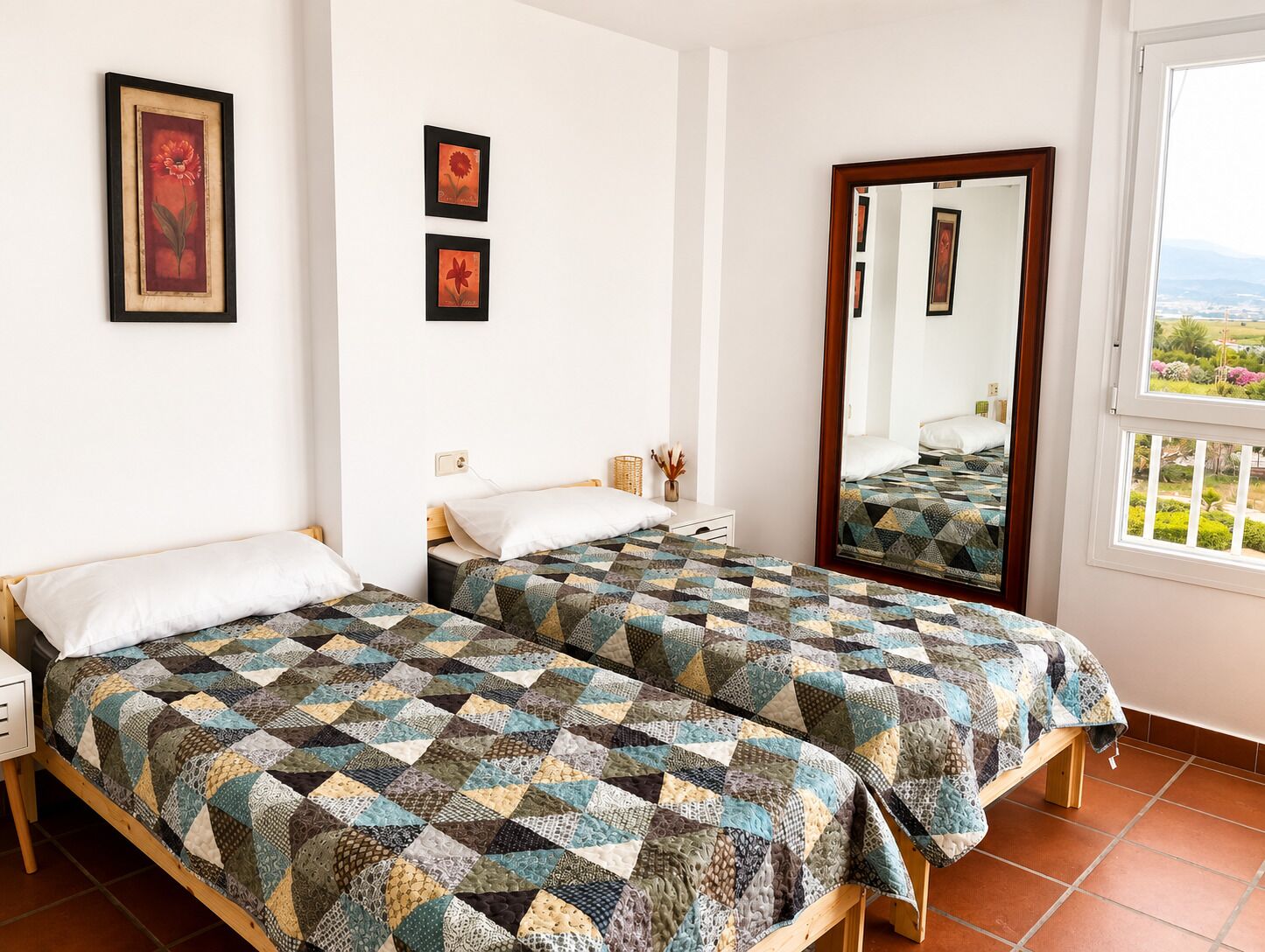 A room with two beds, a large mirror, and framed artwork on the wall.