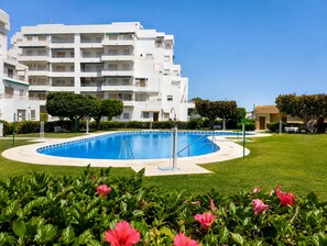 Un hôtel moderne doté d’une piscine, entouré de pelouses bien entretenues et de plantes en fleurs.