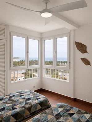 Une pièce dotée d’une grande baie vitrée, d’un ventilateur de plafond et offrant une vue sur la plage.