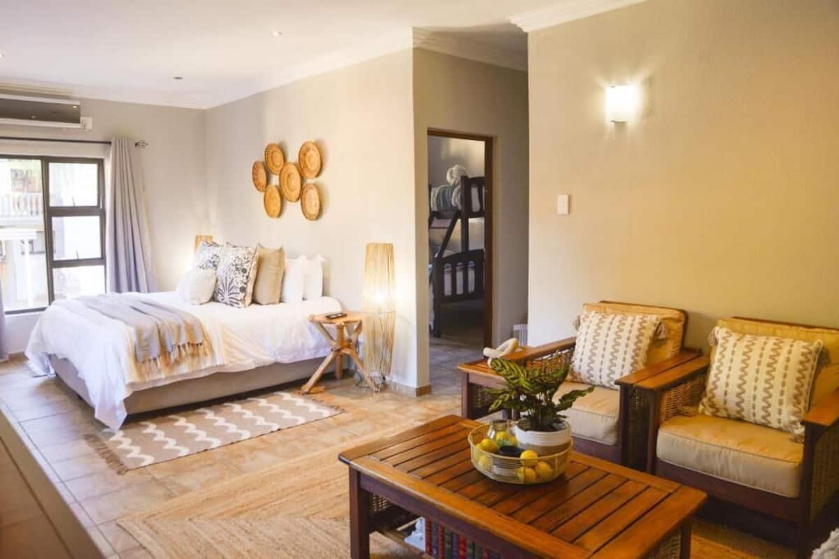 Un dormitorio con cama, mesita de noche, lámpara y vistas a una escalera.