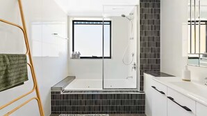 A modern bathroom with a glass-enclosed shower, a white vanity, and a large mirror. - Calm Central - A Sepal Stay (Perth)