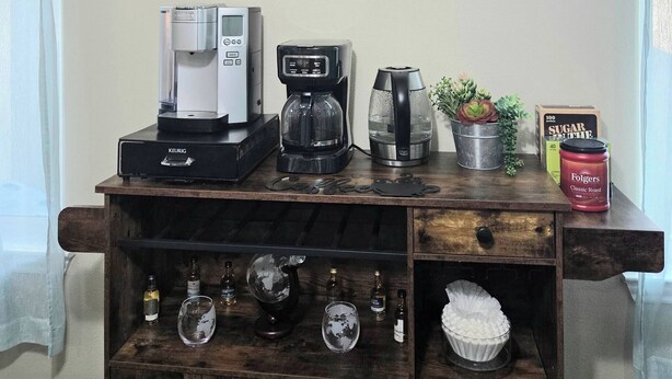 Una estación de café con una máquina Keurig, una cafetera y un tarro de café Folgers.