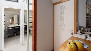 A room with a door labeled 'DREAM,' a wooden floor, a small table with a yellow object, and a window with a view of buildings. - Maison Avec Parking et Terrasse Option spa (Achicourt)
