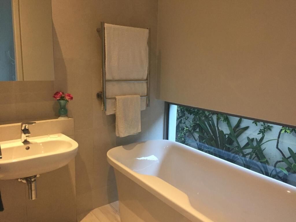 Un baño con lavamanos, bañera y perchero para toallas.