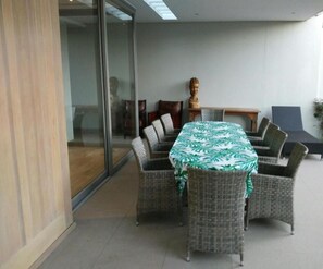 A dining area with a round table, wicker chairs, and a green patterned tablecloth. - 23 Grace (Cape Town)