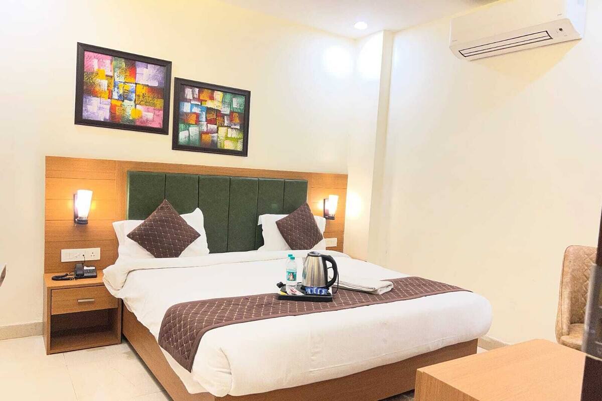 Ein Hotelzimmer mit Bett, Nachttischen, Schreibtisch, Stuhl und zwei Wandbildern.