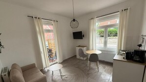 Una cocina moderna con comedor, un sofá y un televisor montado en la pared.