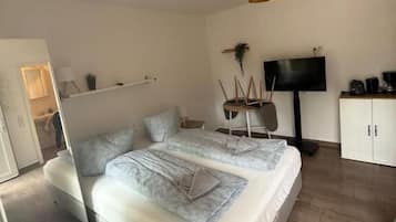Une chambre à coucher comprenant un lit, un téléviseur, une armoire et un luminaire suspendu.