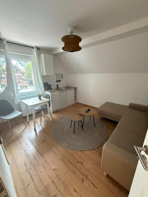 Un espacio habitable compacto con comedor, kitchenette y zona de estar.