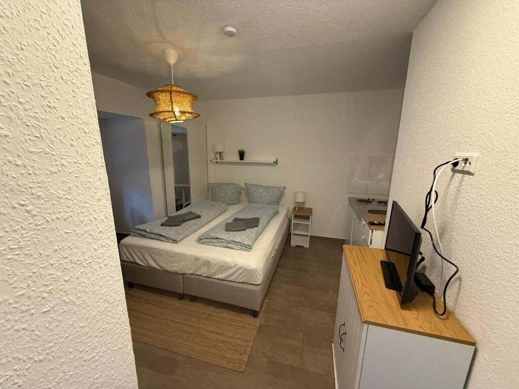 Een slaapkamer met een bed, nachtkastje en een bureau met een computer.