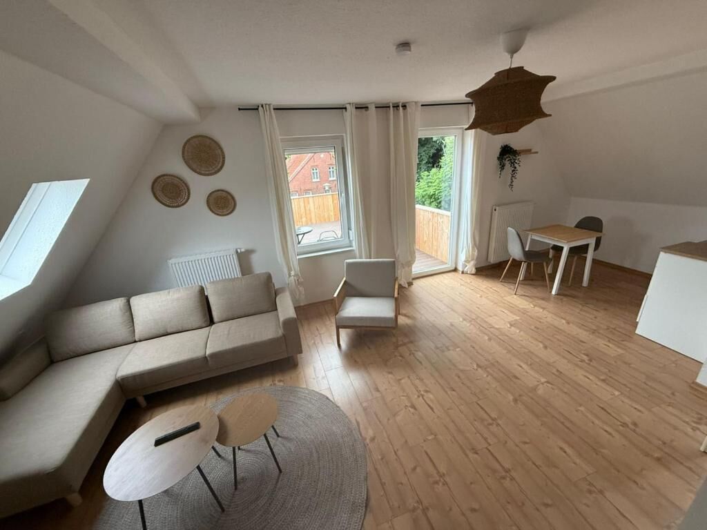 Ein modernes Wohnzimmer mit einer Couch, einem kleinen Tisch, einem Sessel und einem Essbereich.