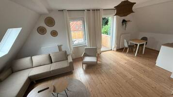 Ein modernes Wohnzimmer mit einer Couch, einem kleinen Tisch, einem Sessel und einem Essbereich.