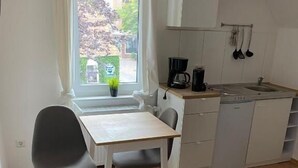 Una cocina pequeña con una mesa de comedor, sillas, una cafetera y una ventana con vistas al exterior.