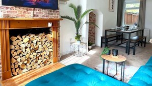 Un saló amb una llar de foc, televisió, zona de dinar i un sofà blau.