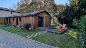 A wooden house with a covered patio, a lawn, and a paved driveway. - House in Mimizan, between the lake and the ocean (Mimizan)