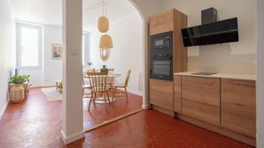 A modern kitchen with wooden cabinets, a built-in oven, and a microwave. - Beautiful, bright, and quiet one-bedroom apartment in the heart of the city, near the Old Port (La Ciotat)