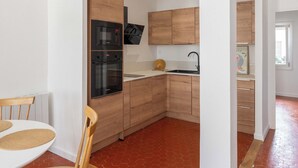 A modern kitchen with wooden cabinets, a built-in oven, and a microwave. - Beautiful, bright, and quiet one-bedroom apartment in the heart of the city, near the Old Port (La Ciotat)