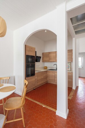 A modern kitchen with wooden cabinets, a built-in oven, and a microwave. - Beautiful, bright, and quiet one-bedroom apartment in the heart of the city, near the Old Port (La Ciotat)
