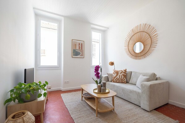 A living room with a sofa, coffee table, and a potted plant. - Beautiful, bright, and quiet one-bedroom apartment in the heart of the city, near the Old Port (La Ciotat)