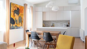 Uma cozinha moderna com armários brancos, bancada de mármore e iluminação pendente.