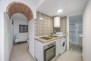 Eine kompakte Küche mit Waschmaschine, Backofen und gefliestem Fliesenspiegel.