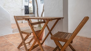 Ein Holztisch mit Stühlen vor einer weißen Wand mit Fliesenboden.
